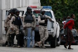 A woman carries a child past police standing guard during a protest led by the art community demanding the resignation of Haitian President Jovenel Moïse, in Petion-Ville, a suburb of Port-au-Prince, Haiti, Oct. 13, 2019.