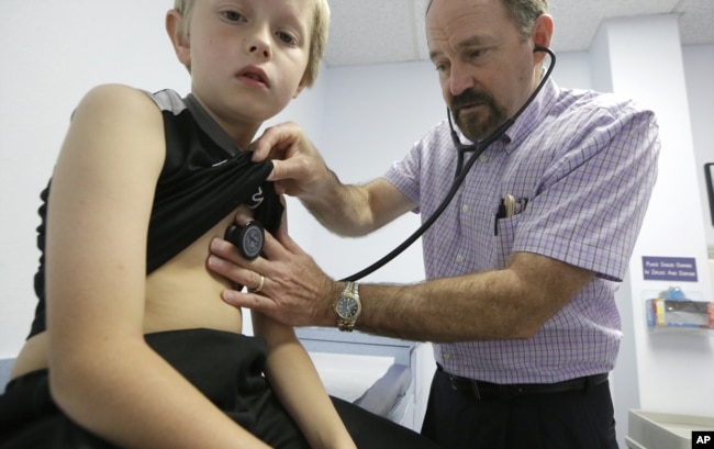 Dr. John Porter examines Connor Russell, 8, during an office visit Tuesday, March 31, 2015, in Richardson, Texas. (AP Photo/LM Otero)