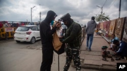 Tentara India tampak mengecek isi tas dari seorang pria Kashmir yang berjalan melewati area pasar yang sibuk di Srinagar pada 11 Oktober 2021. (Foto: AP/Mukhtar Khan)