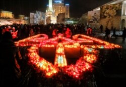 FILE - People light candles placed in the shape of Ukraine's coat of arms, to pay tribute to the victims of the 2013-2014 anti-government protests called the Revolution of Dignity, during commemoration events in central Kiev, Ukraine, Feb. 20, 2017.