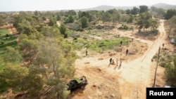 Sukarelawan menanam bibit pohon sebagai bagian dari kampanye penanaman pohon di hutan Al-Nigazah, yang terkena kekeringan akibat perubahan iklim dan kurangnya air hujan, di Khoms, sebelah timur Tripoli, Libya, 23 Oktober 2024. (Ayman al-Sahili/REUTERS)