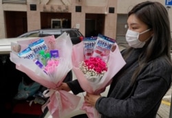 Flower shop owner Iris Leung wears her protective face mask as she delivers flowers with masks to customers on Valentine's Day in Hong Kong, Feb. 14, 2020.
