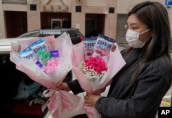 Flower shop owner Iris Leung wears her protective face mask as she delivers flowers with masks to customers on Valentine's Day in Hong Kong, Feb. 14, 2020.
