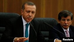 Turkish Prime Minister Tayyip Erdogan addresses the media next to Foreign Minister Ahmet Davutoglu (R) at Esenboga Airport in Ankara, Nov. 21, 2013.