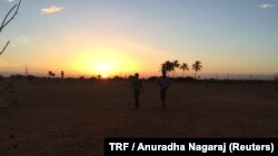 Garment worker Muthulakshmi Mariappan and her brother walk home after an early morning run in a field behind their home in N Pudur village in Tamil Nadu, July 28, 2017.