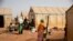 FILE - Displaced women prepare food at Kaya Camp, some 100 kms north of Ouagadougou, Burkina Faso, Feb. 8, 2021. The country's government is at loggerheads with a media outlet over claims displaced women have been forced into sex for food aid. 