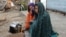 FILE - Internally displaced girls warm up by a stove after their family left their village in the Achin district of Afghanistan, due to clashes between the Islamic State group and other insurgent groups. 
