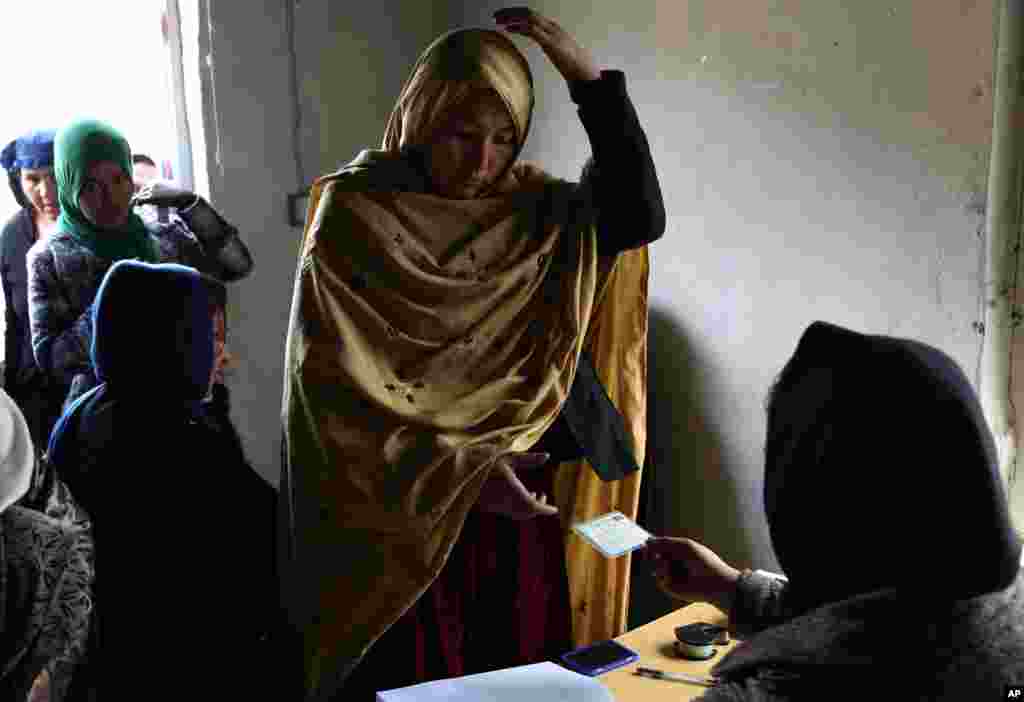 An Afghan woman receives her voter registration card from an employee of the Afghan Independent Election Commission at a women&#39;s voter registration center in Kabul, Afghanistan.