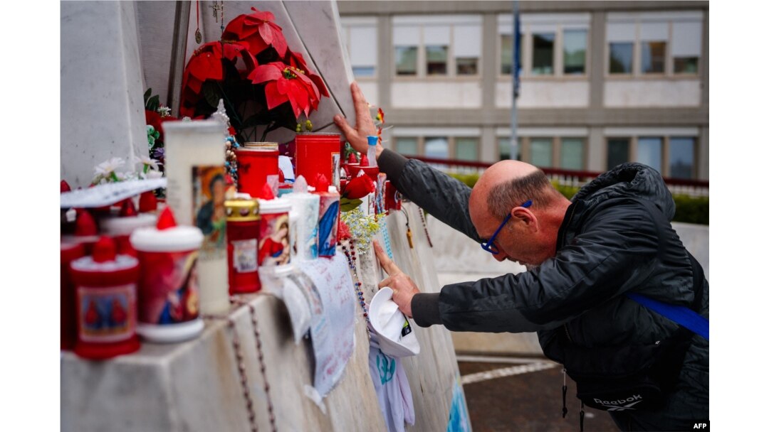 Seorang pria berdoa di depan patung Yohanes Paulus II di Rumah Sakit Universitas Gemelli tempat Paus Fransiskus dirawat karena pneumonia, di Roma pada 1 Maret 2025. (Foto: AFP)