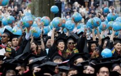 FILE - In this May 30, 2019, file photo, graduates of Harvard's John F. Kennedy School of Government hold aloft inflatable globes as they celebrate graduating during Harvard University's commencement exercises in Cambridge, Mass.