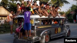 FILE - Residents ride on top of an overcrowded "jeepney", a locally manufactured public transport, along a highway in Mogpog town on Marinduque island in central Philippines, April 8, 2015. 