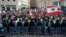 Anti-government protesters hold Lebanese flags and chant slogans as riot police stand guard in front of the government building, in central Beirut, Lebanon, Dec. 23, 2018.