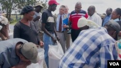 FILE PHOTO: U.S. ambassador to Zimbabwe, Bruce Wharton (in jacket and tie), talking to villagers receiving World Food Program (WFP) food aid in Umguza, a rural area in Matabeleland North province, about 400 kilometers southwest of Harare.