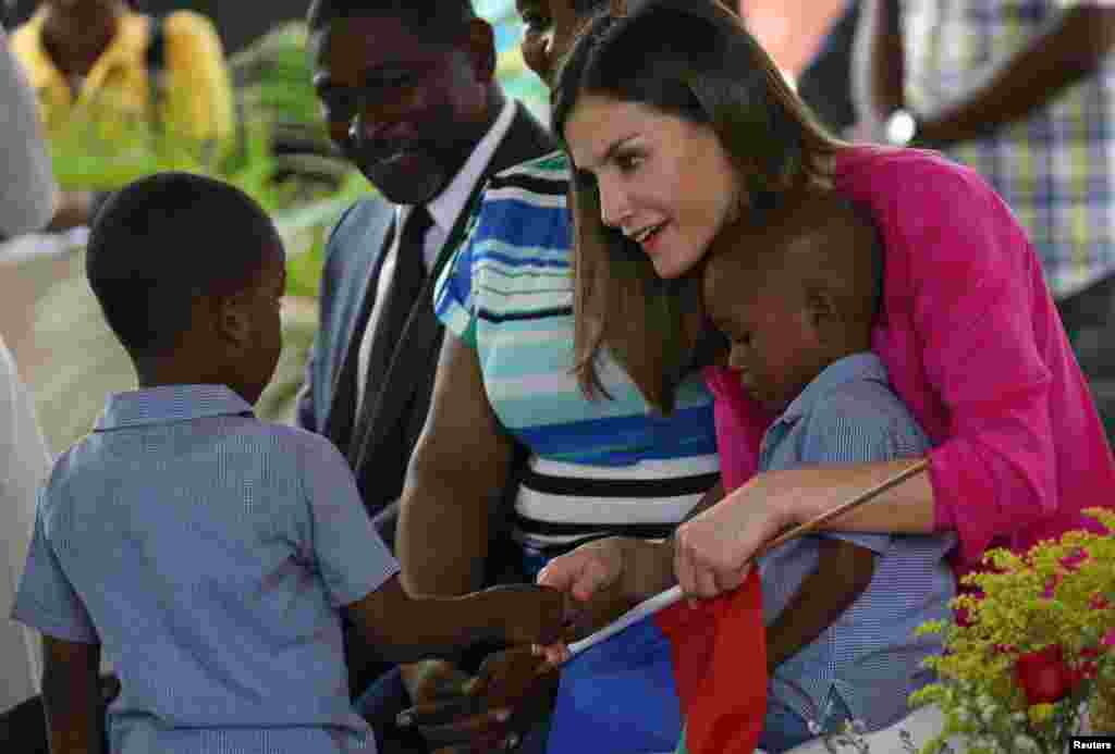 Rèn Espanyòl la Letizia kap bay lamen ak yon ak yon ti gason ki te ba li yon drapo ayisyen pandan vizit li nan Sant Sè yo nan Saint Vincent de Paull nan Site Solèy, Pòtoprens, Ayiti, 23 me, 2018.&nbsp; REUTERS/Andres Martinez Casares - RC12FD9C8700