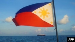 FILE - This handout photo taken April 14, 2021, and received from the Philippine Coast Guard April 15, 2021, a Philippine flag is displayed aboard a coast guard vessel as it patrols in waters off the Spratly Islands.