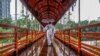 A man wearing protective gear as a preventive measure against the COVID-19 coronavirus walks over a footbridge in Dhaka, Bangladesh.