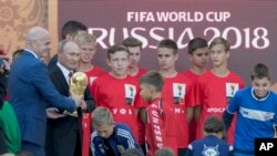 Vladimir Poutine et le président de la Fifa, Gianni Infantino, portent le trophée de la Coupe du monde, Moscou, le 9 septembre 2017.