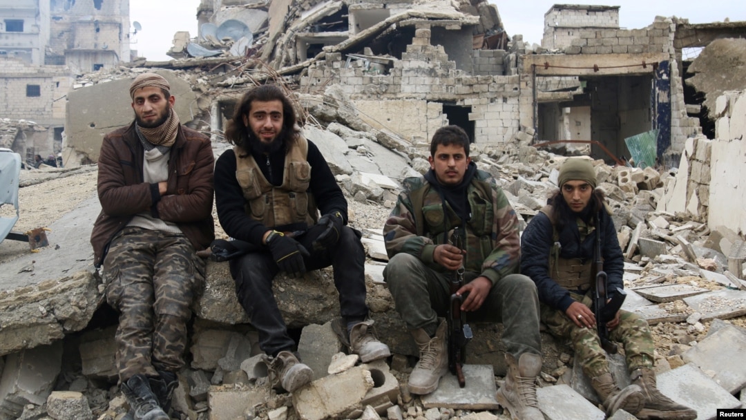Những chiến binh nổi dậy ngồi chờ di tản trên đống đổ nát, Aleppo, Syria, ngày 16 tháng 12 năm 2016. 