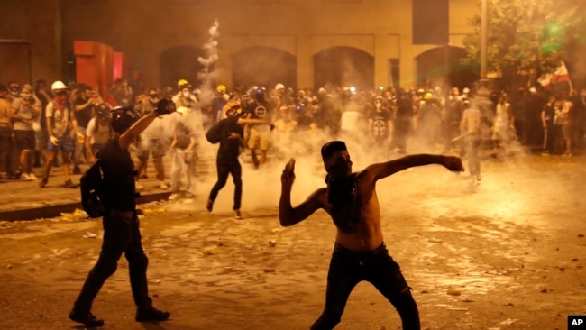 A protester throws stones at Lebanese riot police during a Aug. 9. 2020, anti-government protest following the massive explosion Aug. 4 which devastated Beirut, Lebanon.