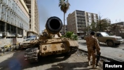 FILE - A member of the Libyan pro-government forces, backed by locals, stands near a tank in Benghazi, Libya. A majority of members (100 out of 196) of the internationally recognized parliament in Tobruk signed a statement Tuesday saying they agree with the latest in a string of plans to establish a unity government with rivals based in Tripoli.