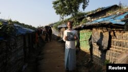 FILE - Noor Islam, from Taung Bazar village in Buthidaung township, poses for a picture with a satellite image of his burnt village in Myanmar, at the Kutupalong camp in Cox's Bazar, Bangladesh, October 15, 2018.