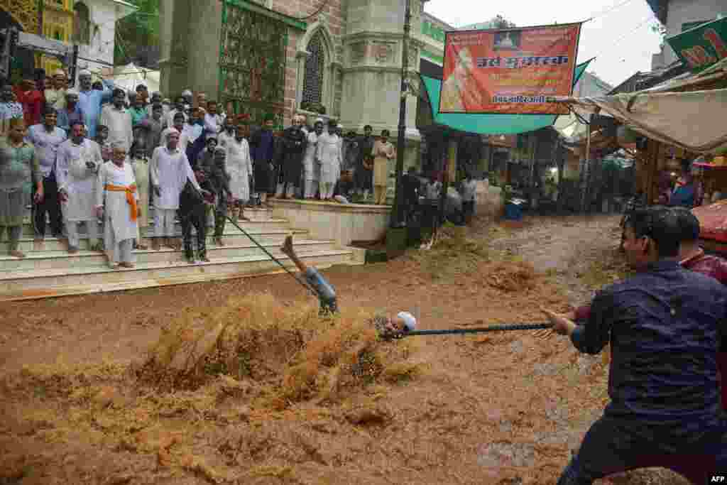 A man falls in rushing flood waters as he tries to hold onto a rope to help people to cross the street, following heavy monsoon rains outside the Moinuddin Chishti sufi shrine in Ajmer in the western Indian state of Rajasthan.