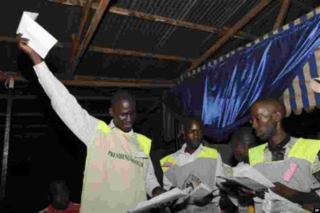 A poll worker holds up a ballot as vote counting begins in Kampala, February 18, 2011