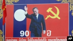 A motorcyclist rides past a poster of late communist leader Kaysone Phomvihane, Vientiane, Laos, March 15, 2011.