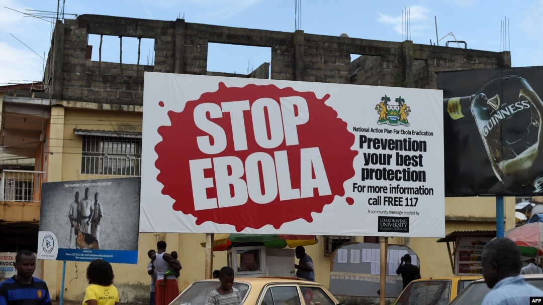 FILES - People walking past a billboard reading "Stop Ebola" in Freetown, Sierra Leone, Nov. 7, 2014. 