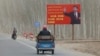 FILE - China's Xi Jinping is seen on a billboard with the slogan, "Administer Xinjiang according to law, unite and stabilize the territory, culturally moisturize the territory, enrich the people and rejuvenate the territory," in Xinjiang Uyghur Autonomous Region, March 21, 2021. 