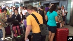 Passengers stand with their luggage outside Terminal 5 at London's Heathrow airport after flights were canceled due to a British Airways IT systems failure, May 27, 2017.