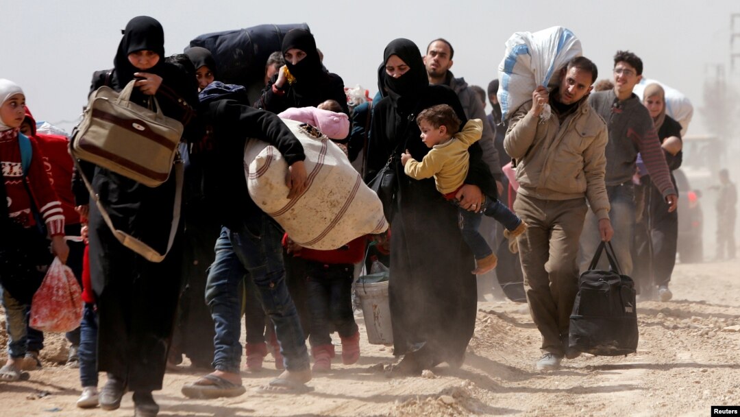 People walk with their belongings as they flee the rebel-held town of Hammouriyeh, eastern Ghouta, Syria, March 15, 2018.