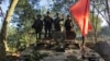 FILE - Members of the Myanmar National Democratic Alliance Army hold the group's flag as they pose for a photograph on a captured army armored vehicle in Myanmar, Oct. 28, 2023.