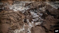 FILE: People work in a mine in Ouagadougou, Burkina Faso, Thursday April 21, 2022. The influx of people displaced by the country's rapidly rising Islamic violence is driving people from the countryside into cities such as the Burkinese capital. 