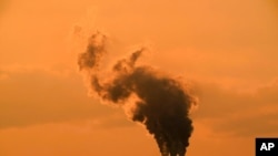 FILE - Smokestacks at the Jeffrey Energy Center coal-fired power plant are silhouetted against the sky at sunset, near Emmet, Kansas, Sept. 12, 2020.