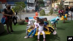 Niños con tapabocas juegan en un rueda en un parque en Caracas, Venezuela. Julio 17, 2020