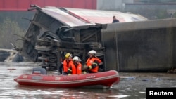 Rescue workers on a small boat search the wreckage of a test TGV train that derailed and crashed in a canal outside Eckwersheim near Strasbourg, eastern France, Nov. 14, 2015.