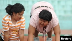 Dua remaja putri sedang berolahraga di kamp musim panas untuk mengurangi berat badan di Shenyang, Provinsi Liaoning, 3 Agustus 2009. (Foto: Reuters/dok)
