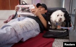 FILE - Stranded passenger Danny Nguyen and his dog Lucky spend the night on the floor of LaGuardia Airport, in New York, July 22, 2013.