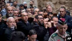 Christian worshippers hold a cross as they walk along the Via Dolorosa towards the Church of the Holy Sepulchre, traditionally believed by many to be the site of the crucifixion of Jesus Christ, during the Good Friday procession in Jerusalem's Old City.