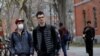 FILE - A student wearing a mask to protect against the coronavirus walks with others at Harvard University, before the school moved its classes to online-only, in Cambridge, Massachusetts, March 10, 2020.