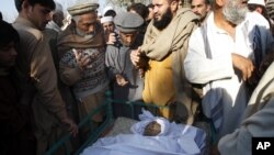 Villagers look at the body of health worker Hilal Khan, who was killed by gunmen in Wahidgari, outside of Peshawar, Pakistan, Dec. 20, 2012. 