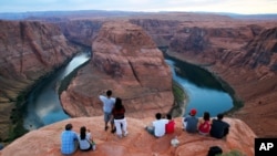 FILE - Visitors view the dramatic bend in the Colorado River at the popular Horseshoe Bend at the Glen Canyon National Recreation Area, in Page, Arizona, Sept. 9, 2011. 