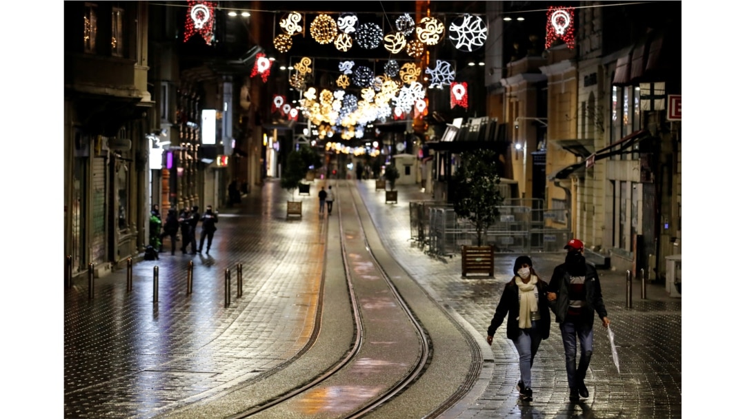 FILE - Couple walks along Istiklal Street at the popular touristic neighbourhood of Beyoglu after a partial weekend curfew started during the COVID-19 outbreak in Istanbul, Turkey, Nov. 21, 2020.