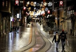 FILE - Couple walks along Istiklal Street at the popular touristic neighbourhood of Beyoglu after a partial weekend curfew started during the COVID-19 outbreak in Istanbul, Turkey, Nov. 21, 2020.