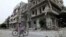 A boy rides a bicycle in front of damaged buildings in Homs, Syria, May 24, 2013. 