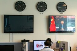 A reporter with the Xinhua Press Agency watches as President Xi Jinping is seen on a video screen remotely addressing the 75th session of the United Nations General Assembly, Sept. 22, 2020, at U.N. headquarters.