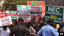 Police provide security as people demonstrate in Abuja, Nigeria, against the postponement of Nigerian elections, Feb. 7, 2015.