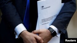 Conservative Party politician Steve Baker holds a Brexit document as British Member of Parliament, Jacob Rees-Mogg, speaks from St Stephen's Entrance at the Houses of Parliament, in London, Britain, Nov. 15, 2018. 