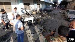 Libyan security forces inspect the remains of a vehicle near the Ministry of Interior in Tripoli after twin blasts hit the Libyan capital, August 19, 2012.